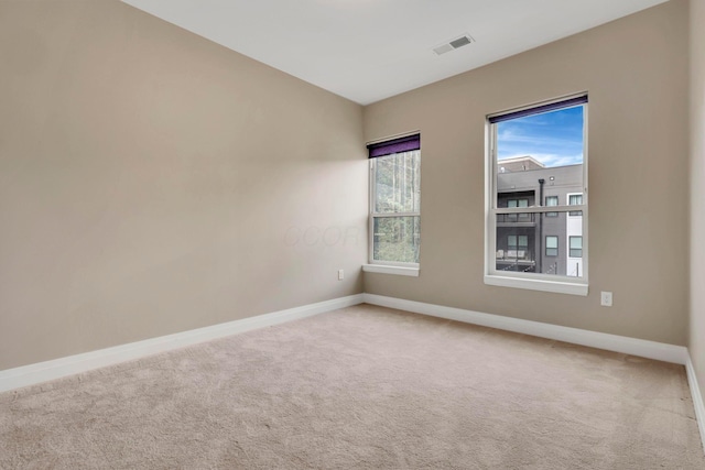 carpeted spare room featuring baseboards and visible vents