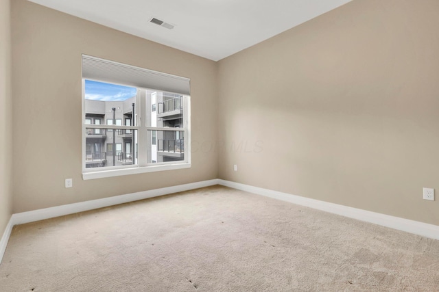 spare room with carpet, visible vents, and baseboards