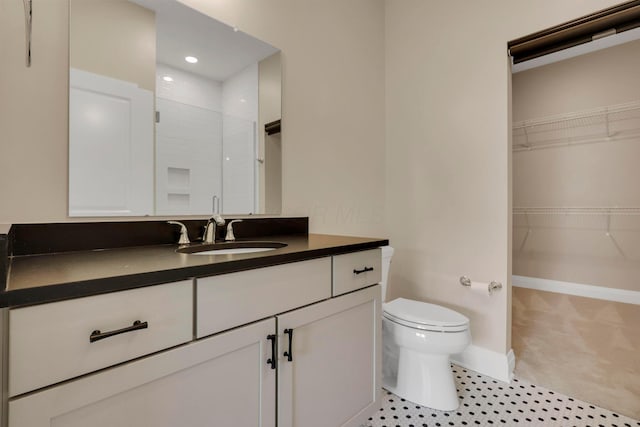 bathroom featuring toilet, a spacious closet, a shower, and vanity