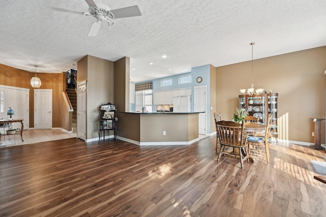 kitchen featuring dark countertops, freestanding refrigerator, a textured ceiling, wood finished floors, and a peninsula