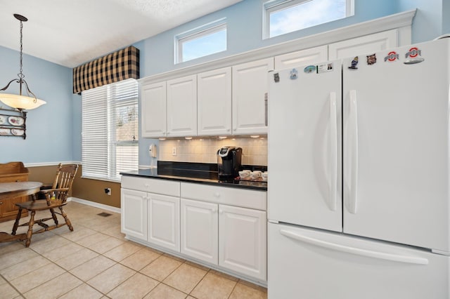 kitchen featuring freestanding refrigerator, backsplash, a healthy amount of sunlight, and dark countertops