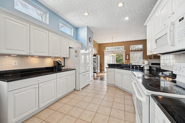 kitchen featuring backsplash, light tile patterned flooring, a sink, white appliances, and a peninsula