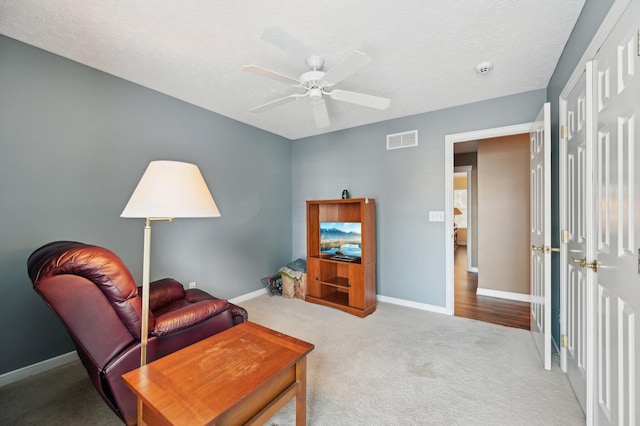 sitting room with carpet floors, visible vents, ceiling fan, and baseboards