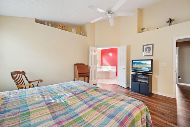 bedroom featuring high vaulted ceiling, ensuite bath, baseboards, and wood finished floors