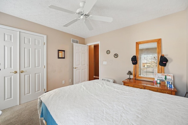 bedroom with a textured ceiling, ceiling fan, carpet flooring, visible vents, and a closet