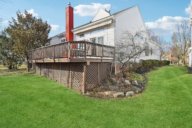 rear view of house featuring a yard, a chimney, and a wooden deck