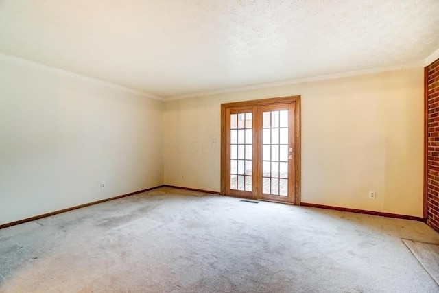 carpeted spare room featuring baseboards, visible vents, ornamental molding, and a textured ceiling