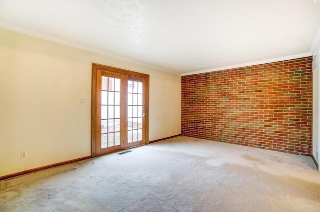 carpeted empty room with baseboards, brick wall, visible vents, and crown molding