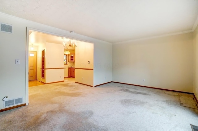 empty room featuring light colored carpet, visible vents, crown molding, and baseboards