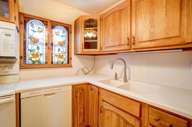 kitchen with white appliances, glass insert cabinets, light countertops, and a sink