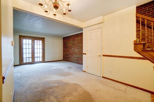 carpeted spare room with a chandelier, brick wall, and baseboards