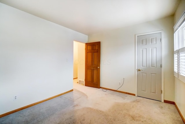 unfurnished bedroom with light colored carpet and baseboards