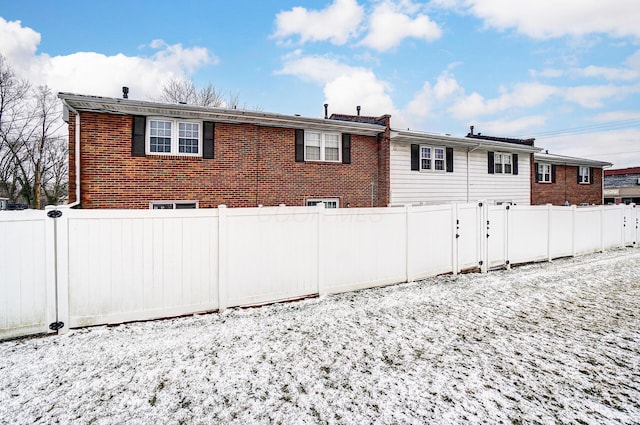 rear view of house featuring brick siding and fence