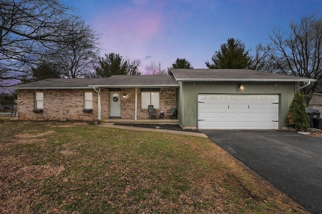 ranch-style home featuring a garage, brick siding, a front lawn, and aphalt driveway