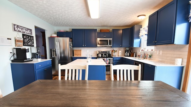 kitchen featuring stainless steel appliances, a sink, a center island, and blue cabinets