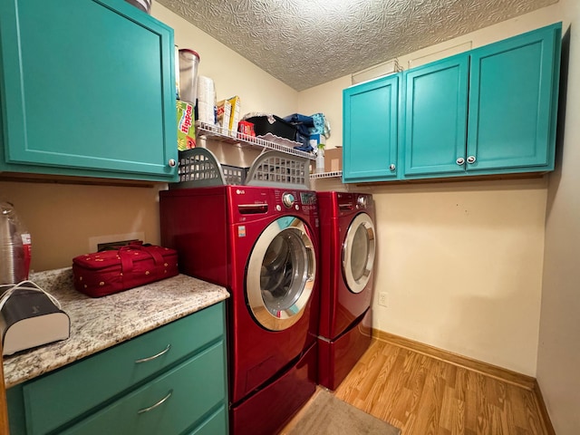 laundry room with a textured ceiling, wood finished floors, baseboards, cabinet space, and washing machine and clothes dryer