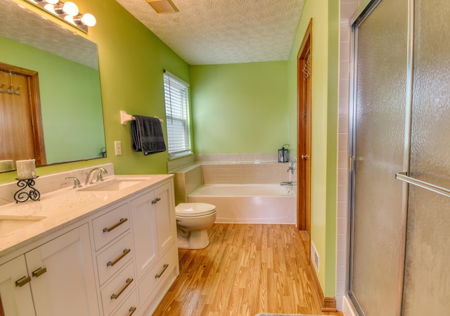 full bath with a textured ceiling, a garden tub, wood finished floors, a sink, and a shower stall