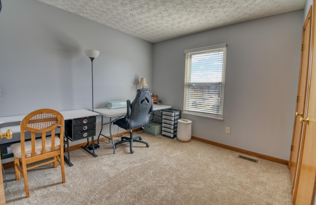 office area featuring a textured ceiling, carpet flooring, visible vents, and baseboards