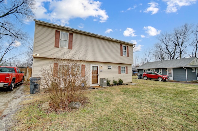 back of property with a yard, driveway, and fence