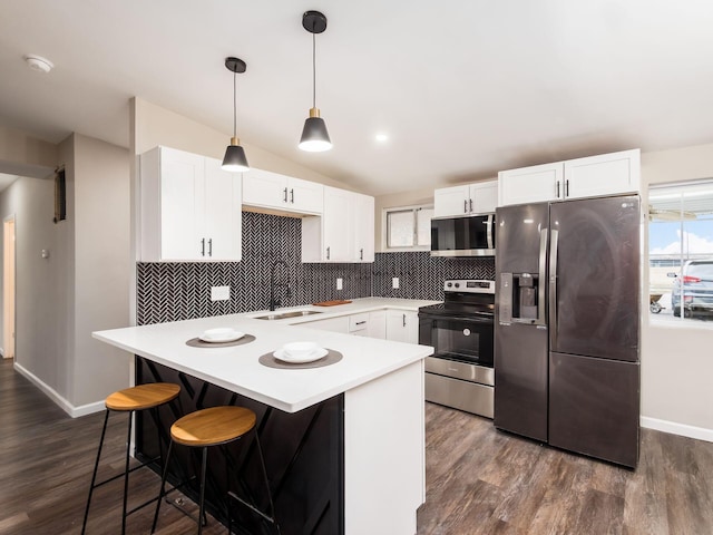 kitchen with appliances with stainless steel finishes, a sink, white cabinets, and tasteful backsplash