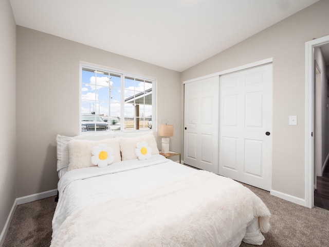 bedroom featuring lofted ceiling, a closet, baseboards, and carpet flooring