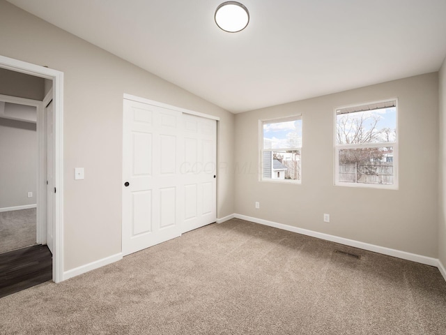 unfurnished bedroom with carpet floors, baseboards, visible vents, and lofted ceiling