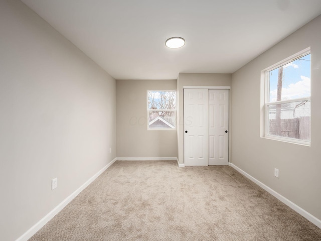 unfurnished bedroom with carpet flooring, multiple windows, and baseboards