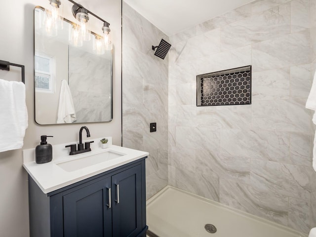 full bath featuring tiled shower and vanity