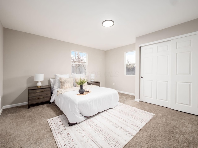 bedroom with light carpet, multiple windows, and baseboards