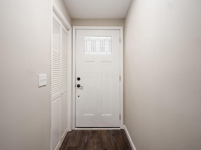 doorway to outside featuring baseboards and dark wood finished floors