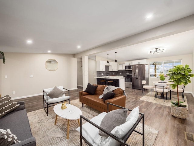 living room with recessed lighting, visible vents, baseboards, and wood finished floors