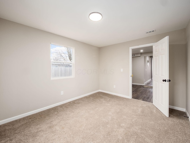 unfurnished room featuring dark colored carpet, visible vents, and baseboards