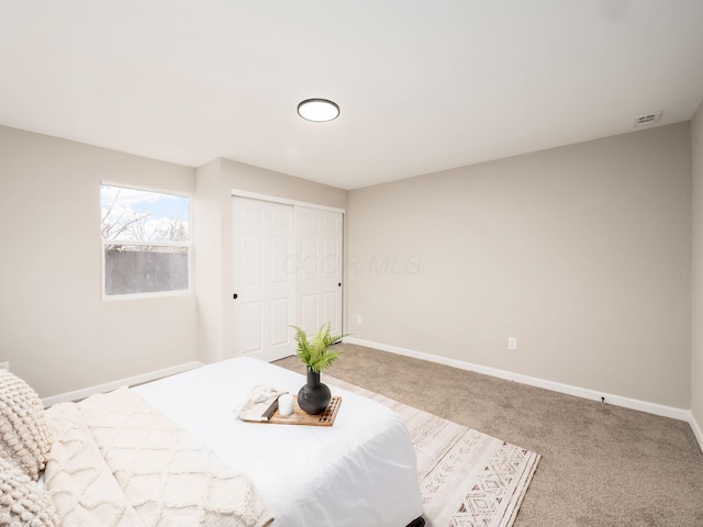 bedroom with carpet, visible vents, baseboards, and a closet