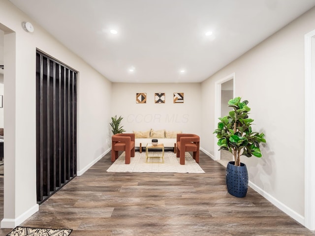 living area with baseboards, wood finished floors, and recessed lighting