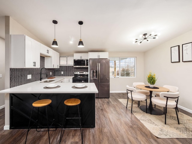 kitchen featuring appliances with stainless steel finishes, light countertops, a sink, and decorative backsplash