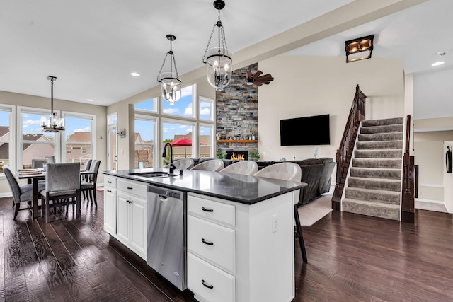 7179 Seymour Ct, Canal Winchester, OH 43110 - kitchen with stainless steel dishwasher, a chandelier, dark countertops, dark wood finished floors, and a fireplace