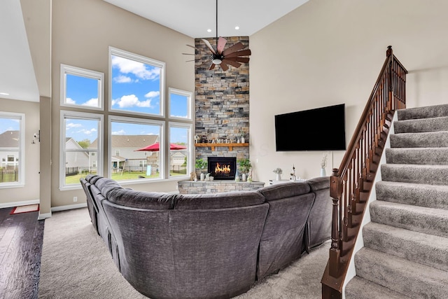 7179 Seymour Ct, Canal Winchester, OH 43110 - living room with carpet floors, a ceiling fan, a stone fireplace, stairs, and a high ceiling