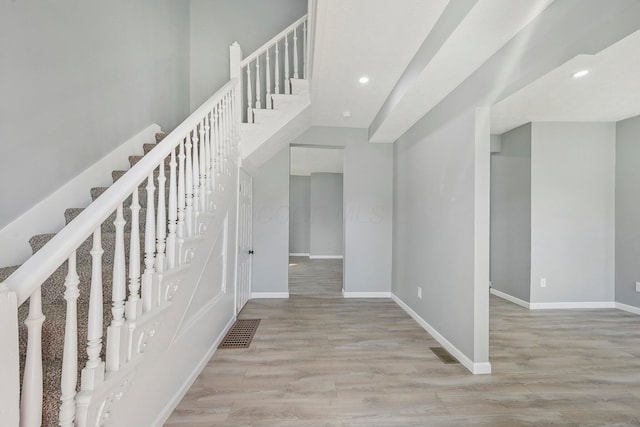 stairs featuring wood finished floors, visible vents, and baseboards