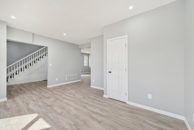 unfurnished living room featuring stairway, light wood-style flooring, visible vents, and baseboards