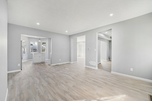 unfurnished living room featuring light wood-style flooring, recessed lighting, and baseboards