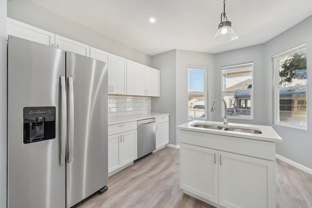 kitchen with a sink, stainless steel appliances, light countertops, white cabinetry, and tasteful backsplash