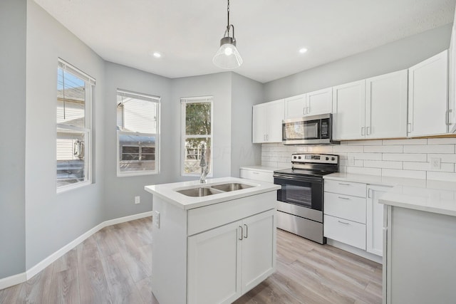 kitchen featuring light wood-type flooring, a sink, backsplash, stainless steel appliances, and baseboards