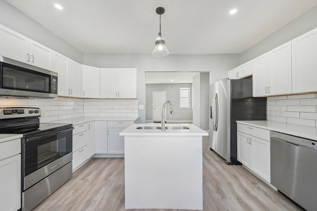 kitchen with a center island with sink, light countertops, light wood-style flooring, stainless steel appliances, and a sink