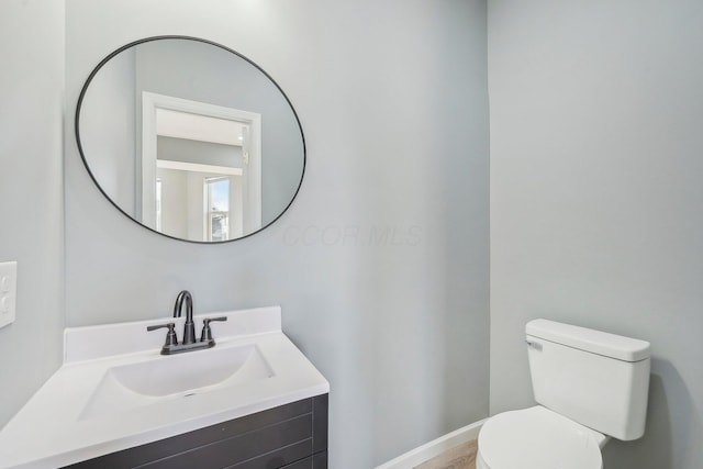 bathroom featuring toilet, vanity, and baseboards