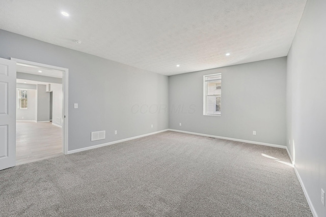 empty room featuring recessed lighting, carpet, and visible vents