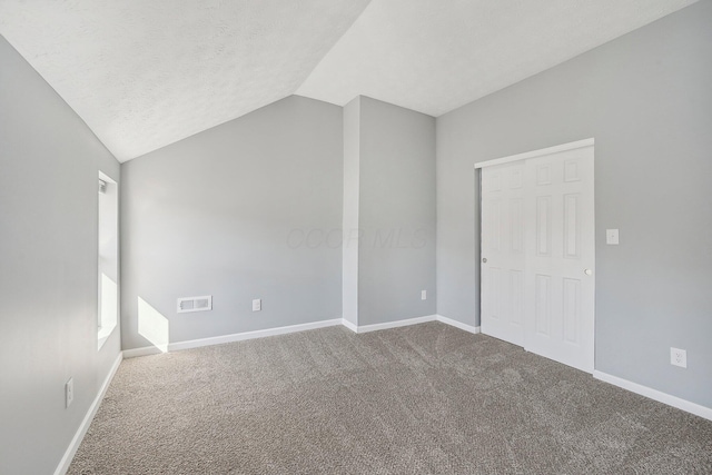 spare room with visible vents, lofted ceiling, carpet, and baseboards