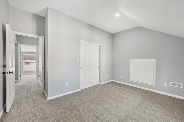 unfurnished bedroom featuring visible vents, baseboards, carpet, and vaulted ceiling