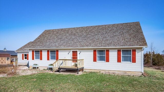 view of front of property featuring a wooden deck, a front yard, and roof with shingles