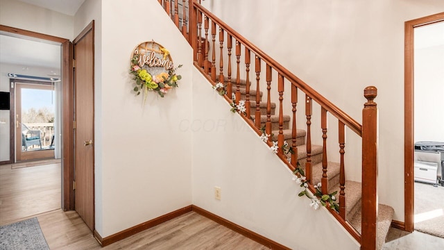 staircase featuring baseboards and wood finished floors