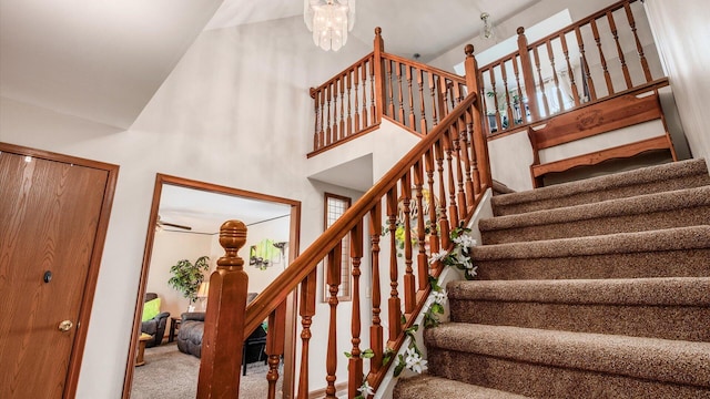 staircase with an inviting chandelier, a towering ceiling, and carpet floors